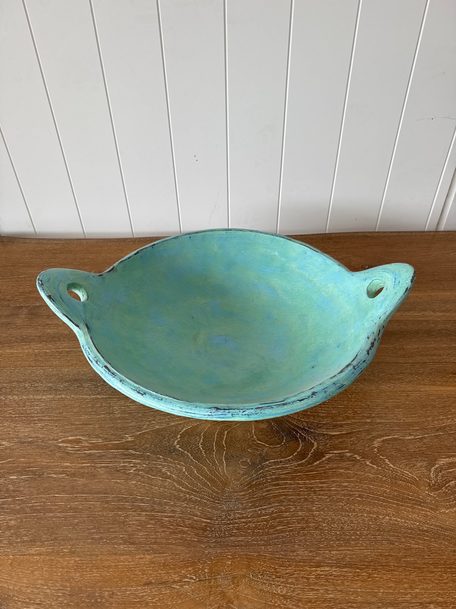 turquoise fruit bowl with handles on a wooden table