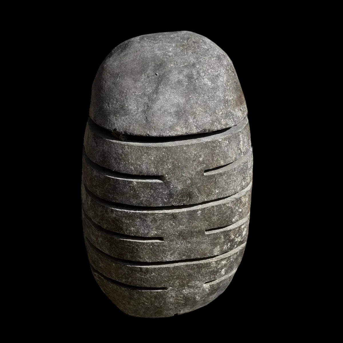 A gray slotted stone lamp, with visible natural stone texture and slots for light diffusion.