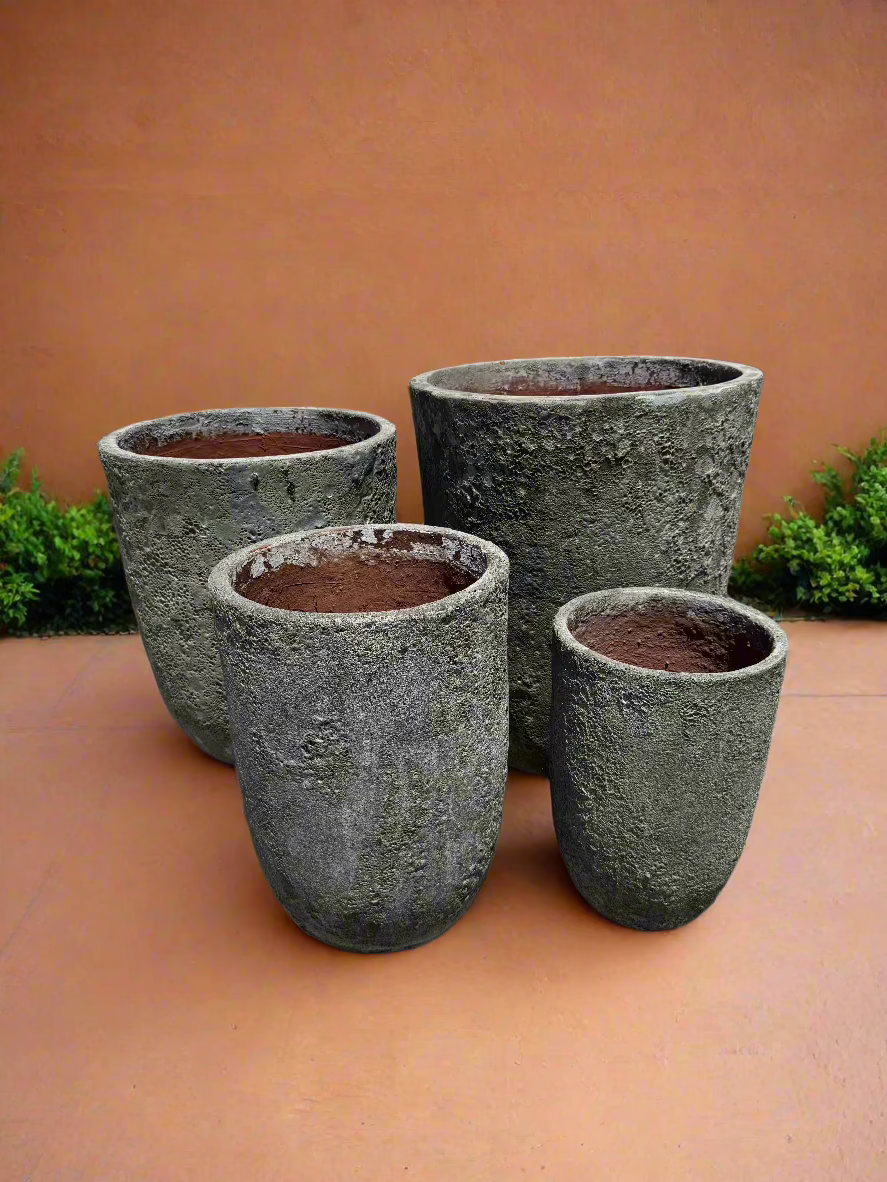 Atlantis lava rock tall u pots in four different sizes in front of a rendered orange wall on top of terracotta tiles
