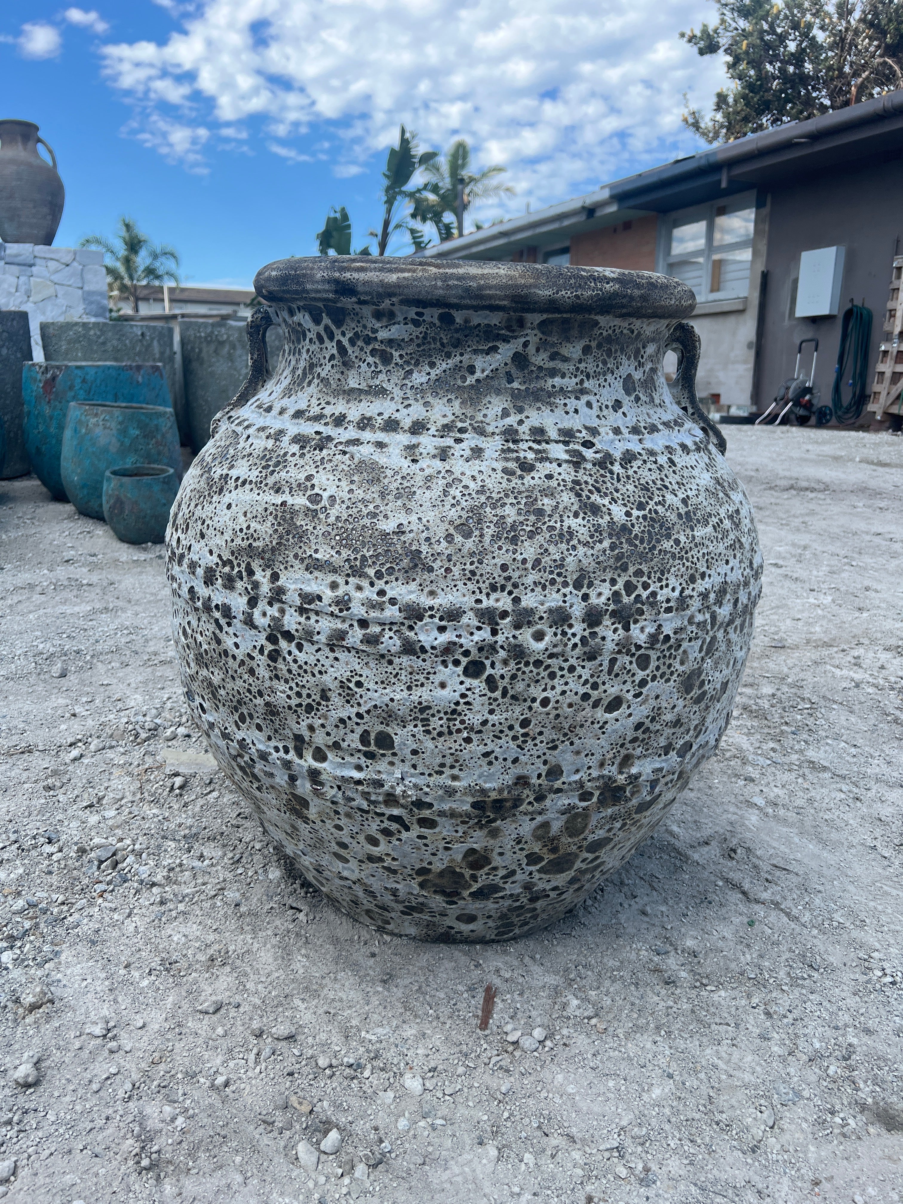 Lava rock Atlantis garden pot urn with handles in beige colour outside in a yard