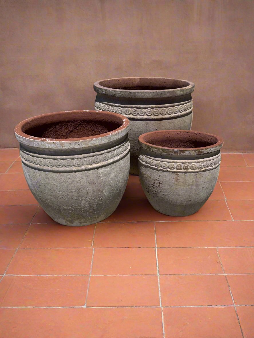 ancient Vietnamese coin garden pots on terracotta tiles next to a rendered orange red wall