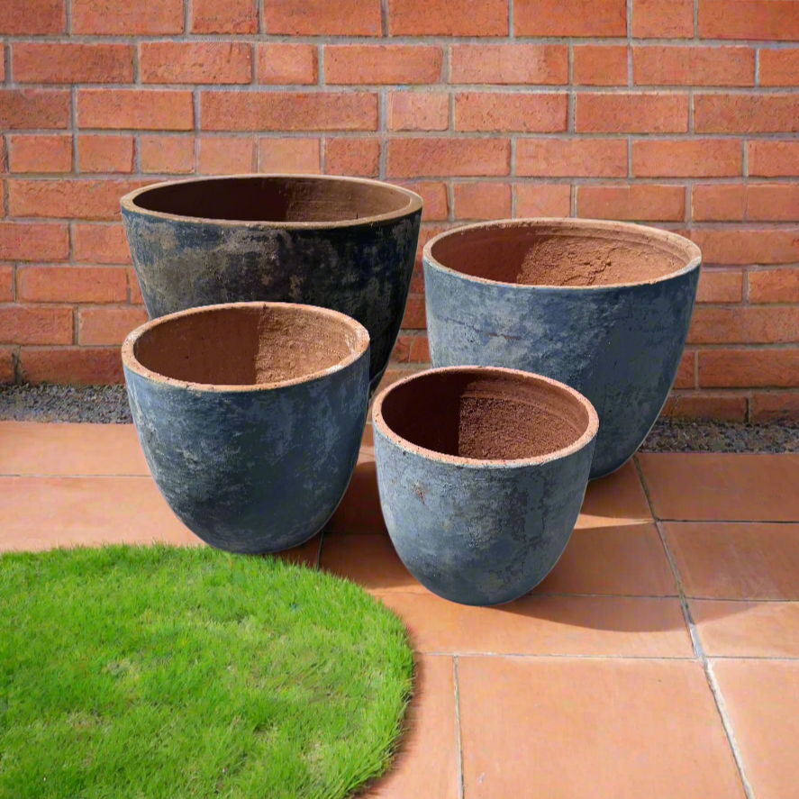 ancient vietamese blue egg pots in a garden next to a brick wall