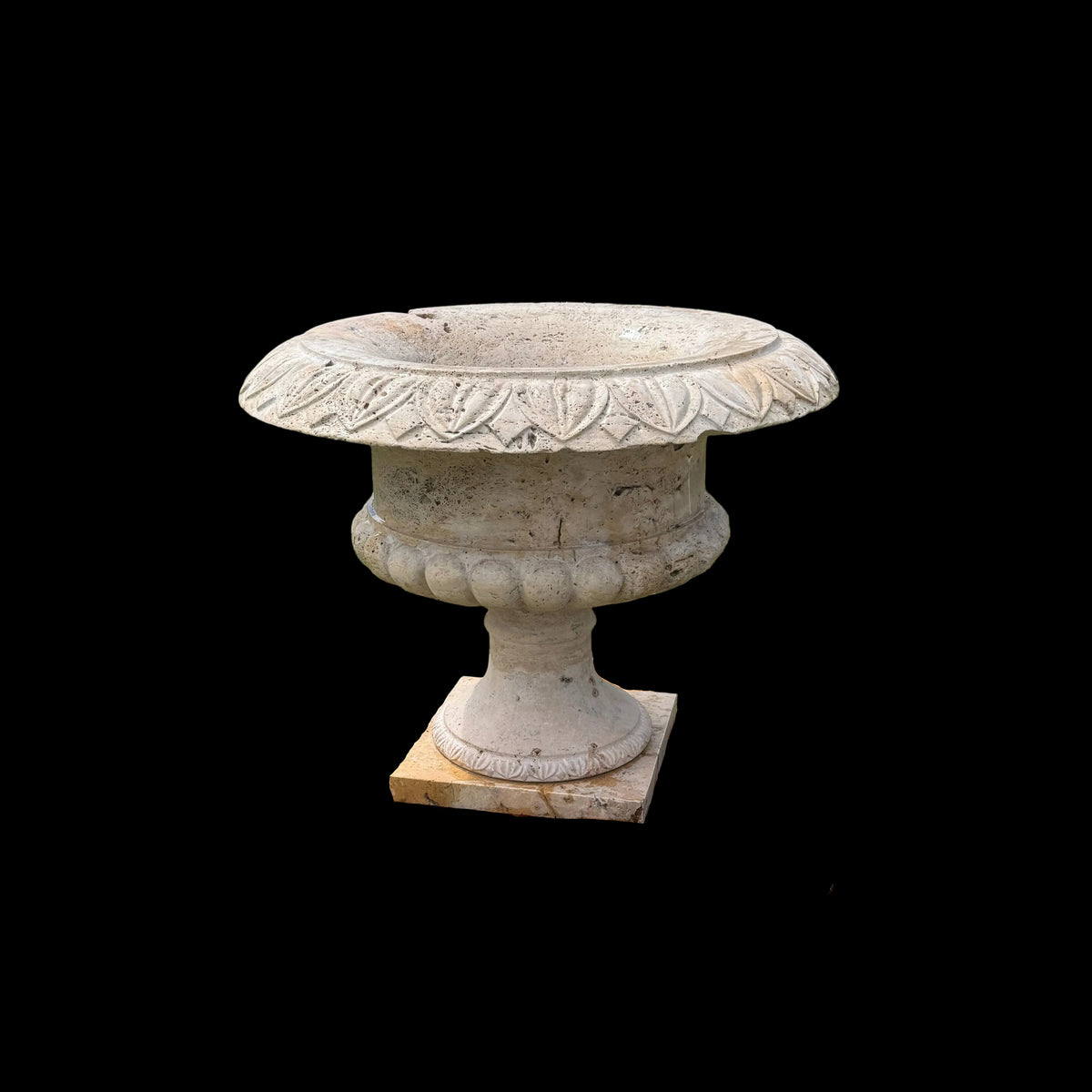 Decorative stone bird bath on a grassy area with a house in the background