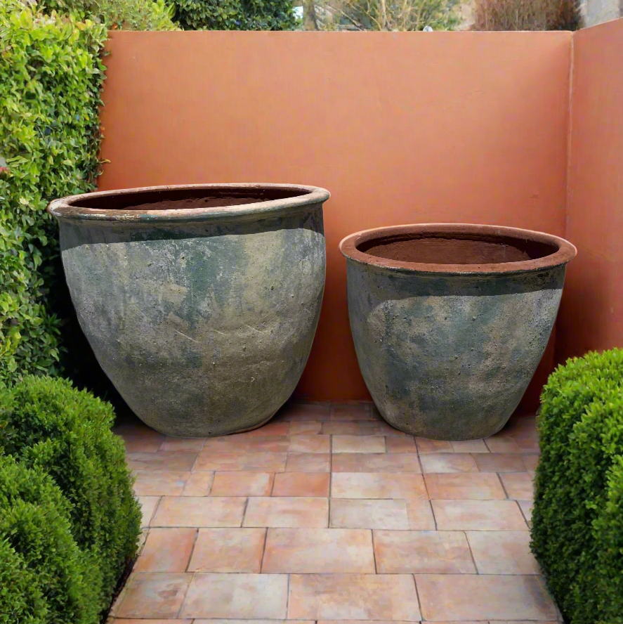 xl ancient blue vietnamese round tree planters in two sizes next to a rendered terracotta wall in a garden