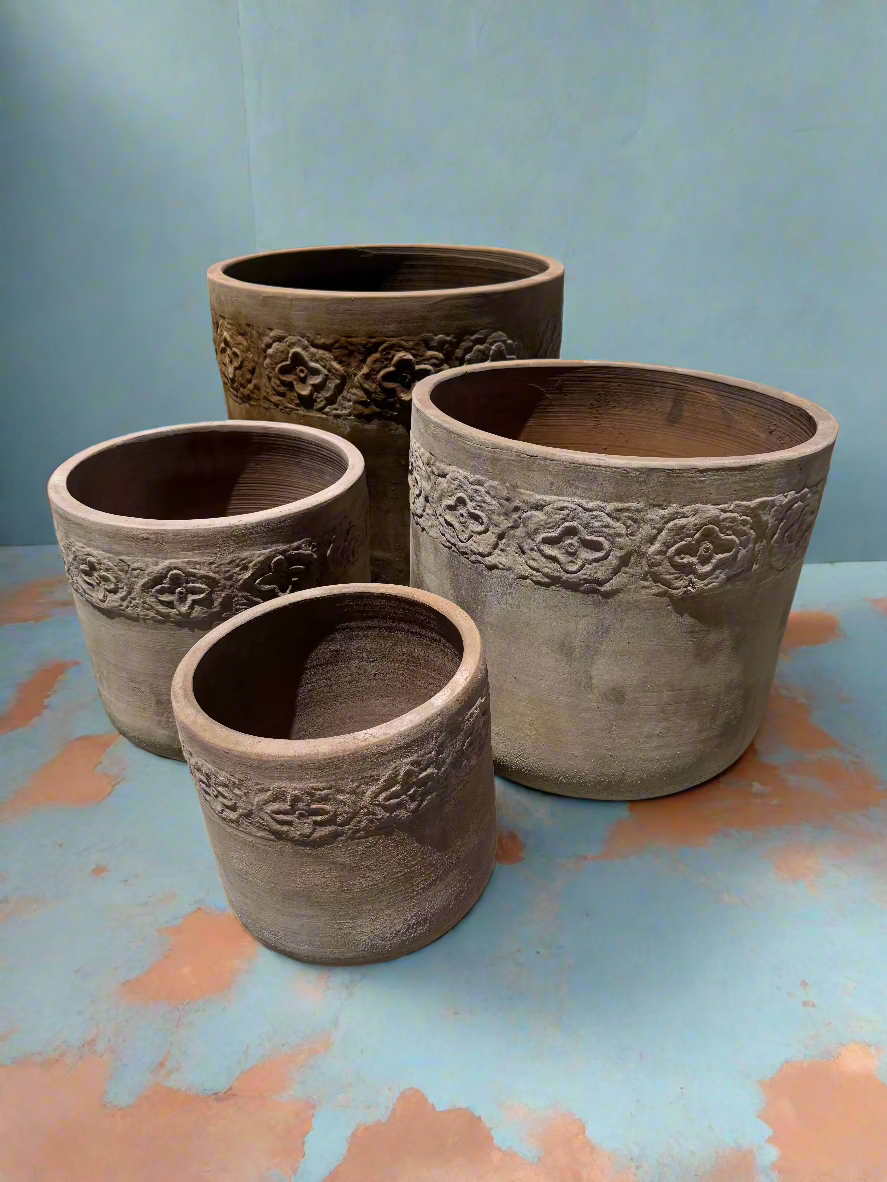 Ancient Terracotta low U pots in four different sizes in a blue room on a terracotta floor