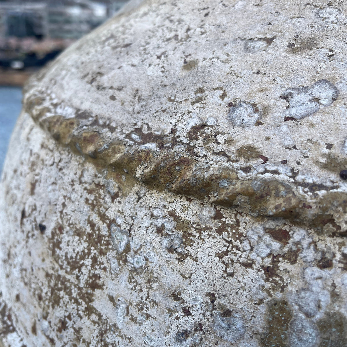 Close-up detail of a weathered stone or concrete surface with a textured, mossy, and lichen-covered finish.