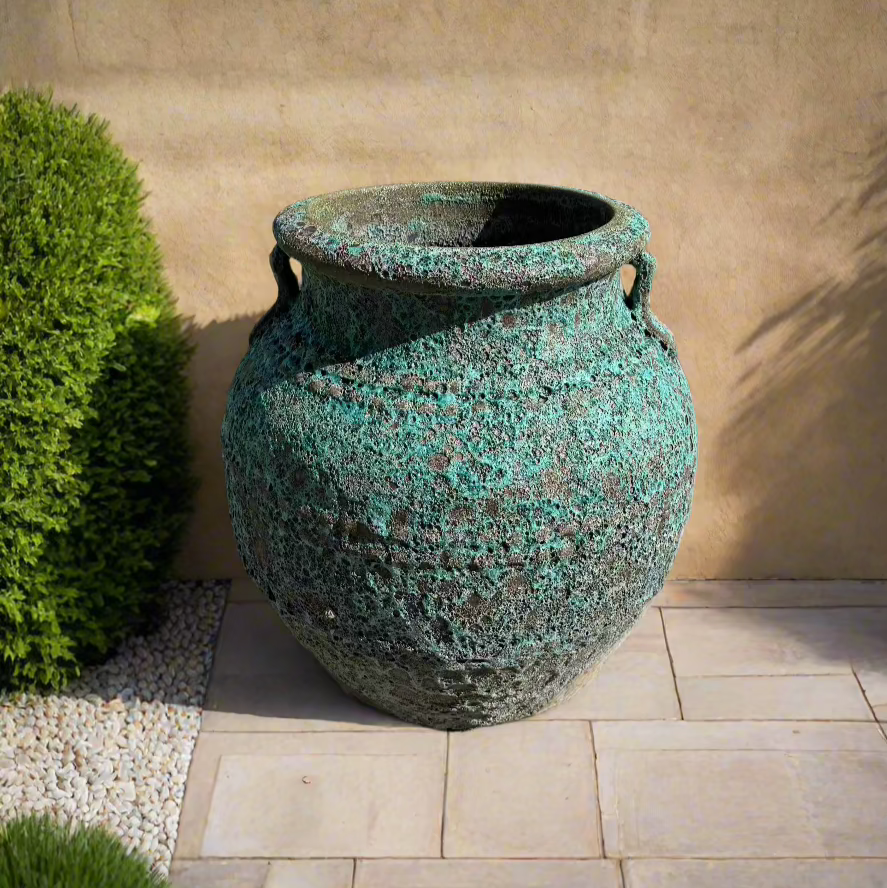 Green Lava Rock Atlantis Garden Urn on Natural Stone Garden Tiles in front of a yellow render wall
