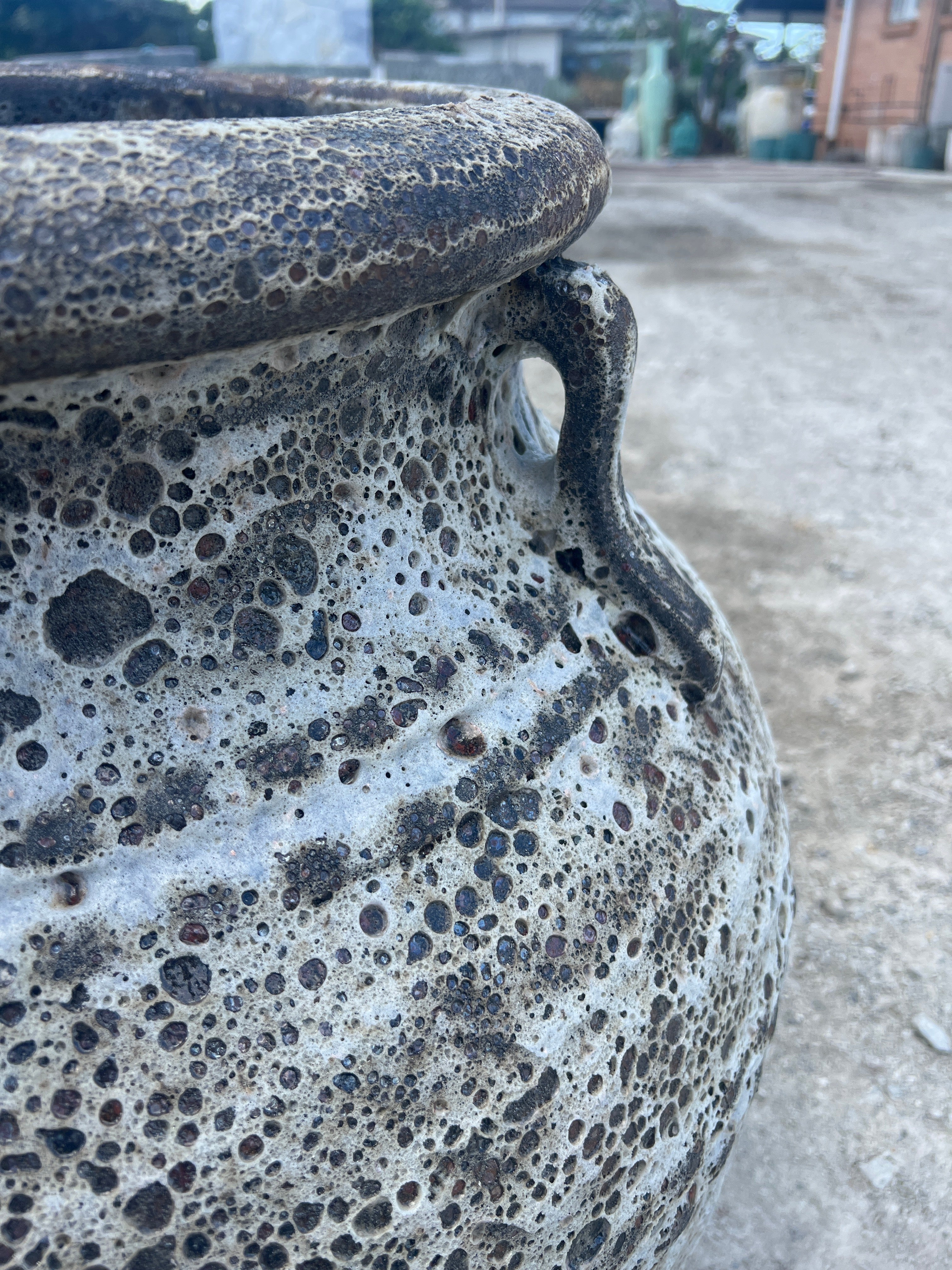 Lava rock Atlantis garden pot urn with handles in beige colour outside in a yard