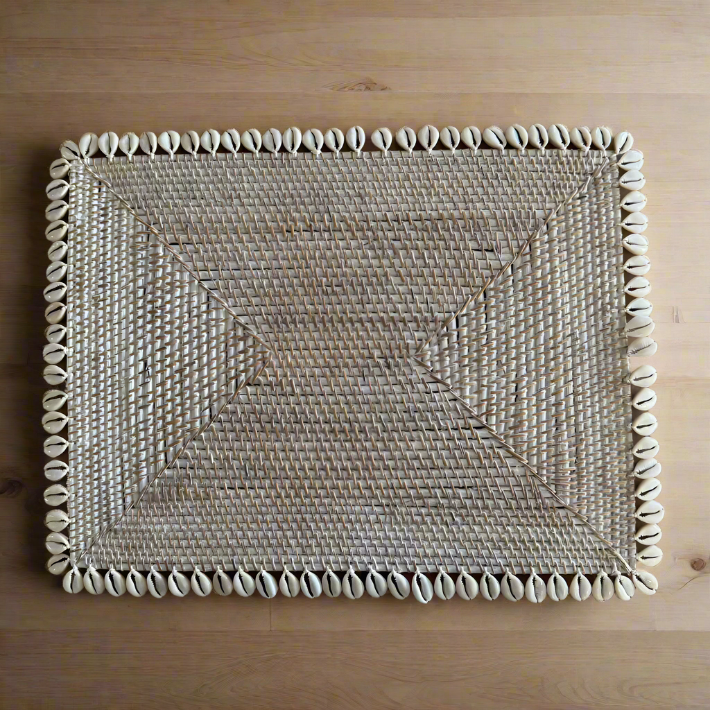 Rectangular Rattan dining table placemat with cowrie shell border on a timber table 