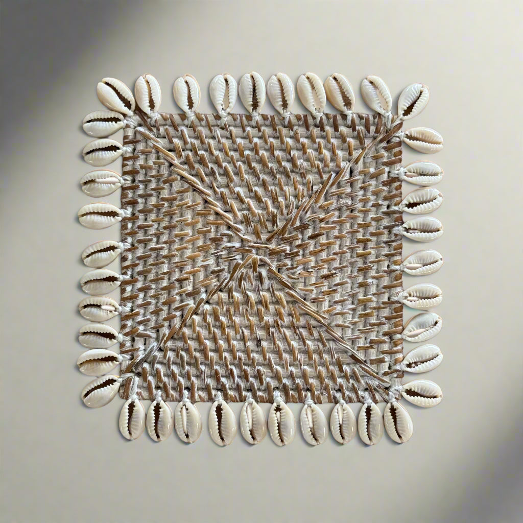 Square rattan coaster with a cowrie shell border on table top