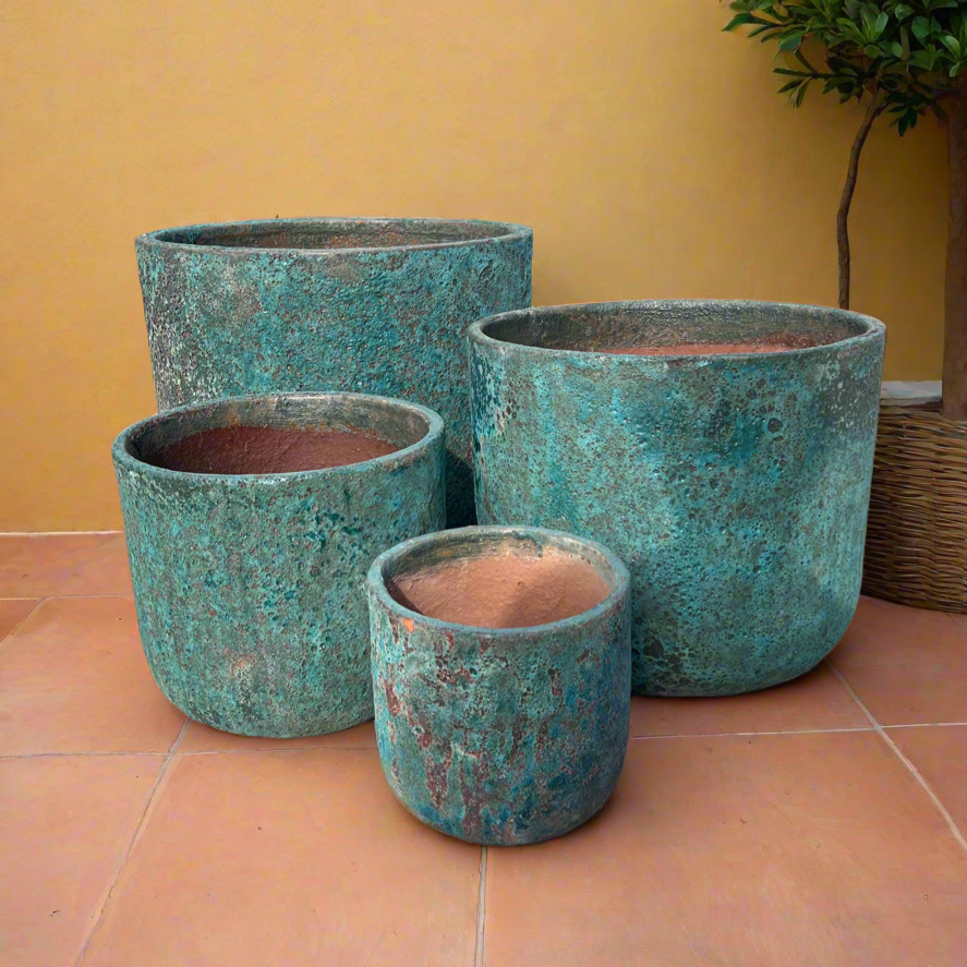 Turquoise Lava Rock Atlantis Low U Ceramic Garden Pot in four sizes on terra cotta tiles with a beautiful yellow render wall