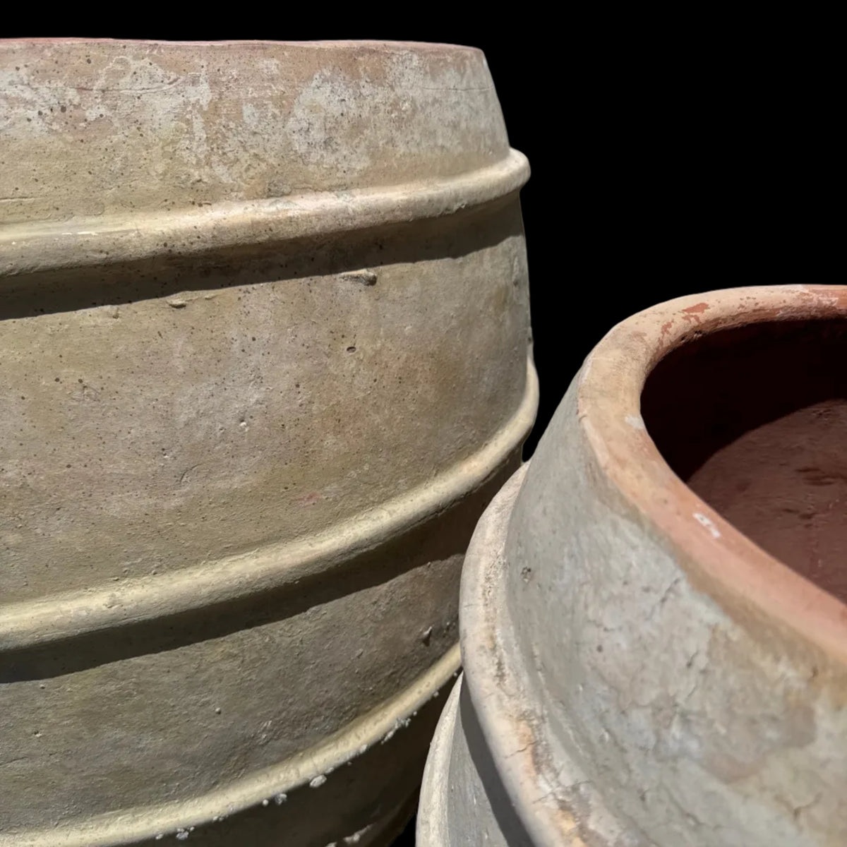 a close up of two terracotta ribbed band tree planters and their ancient washed patinas