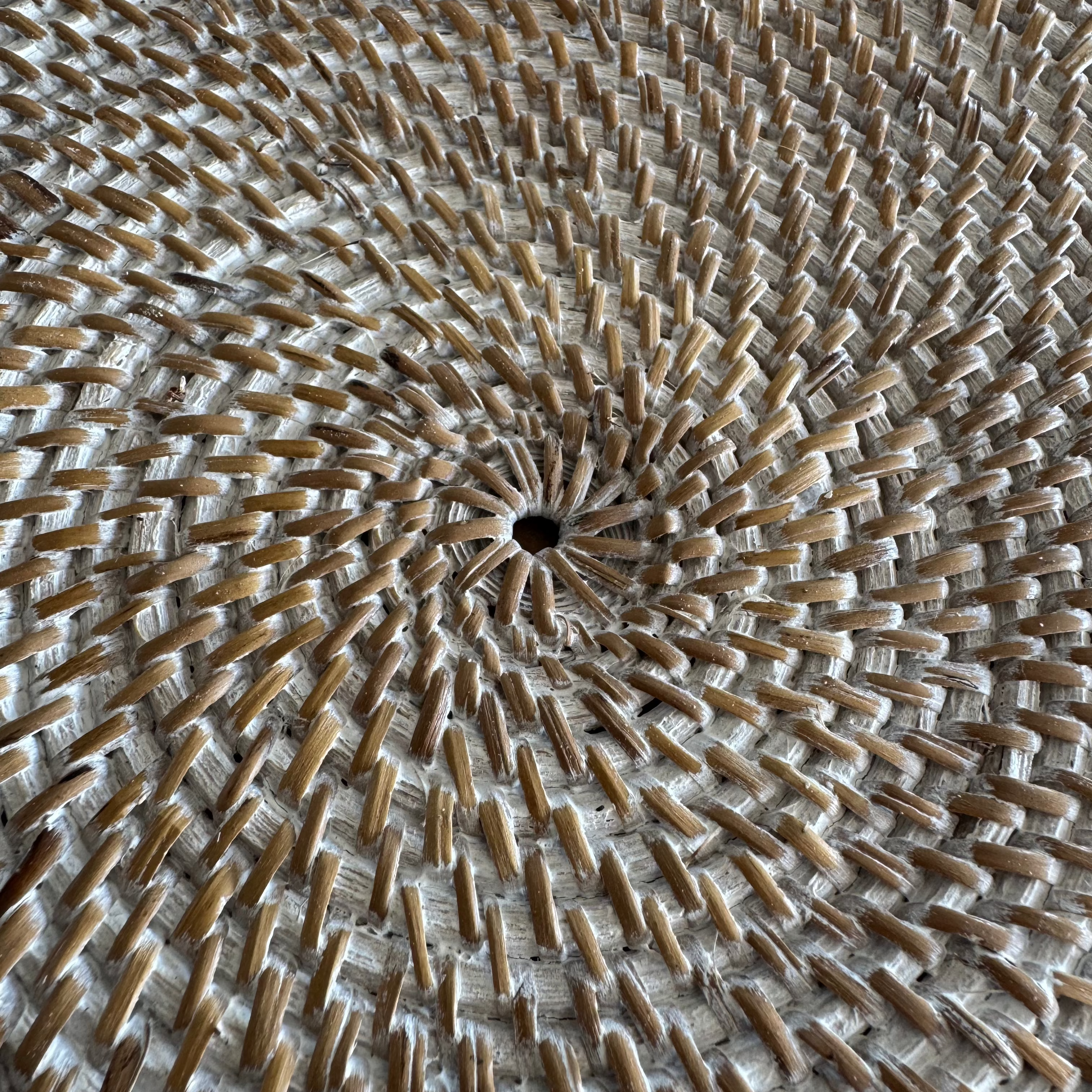 a close up of the handmade round rattan placemat with cowrie shell border