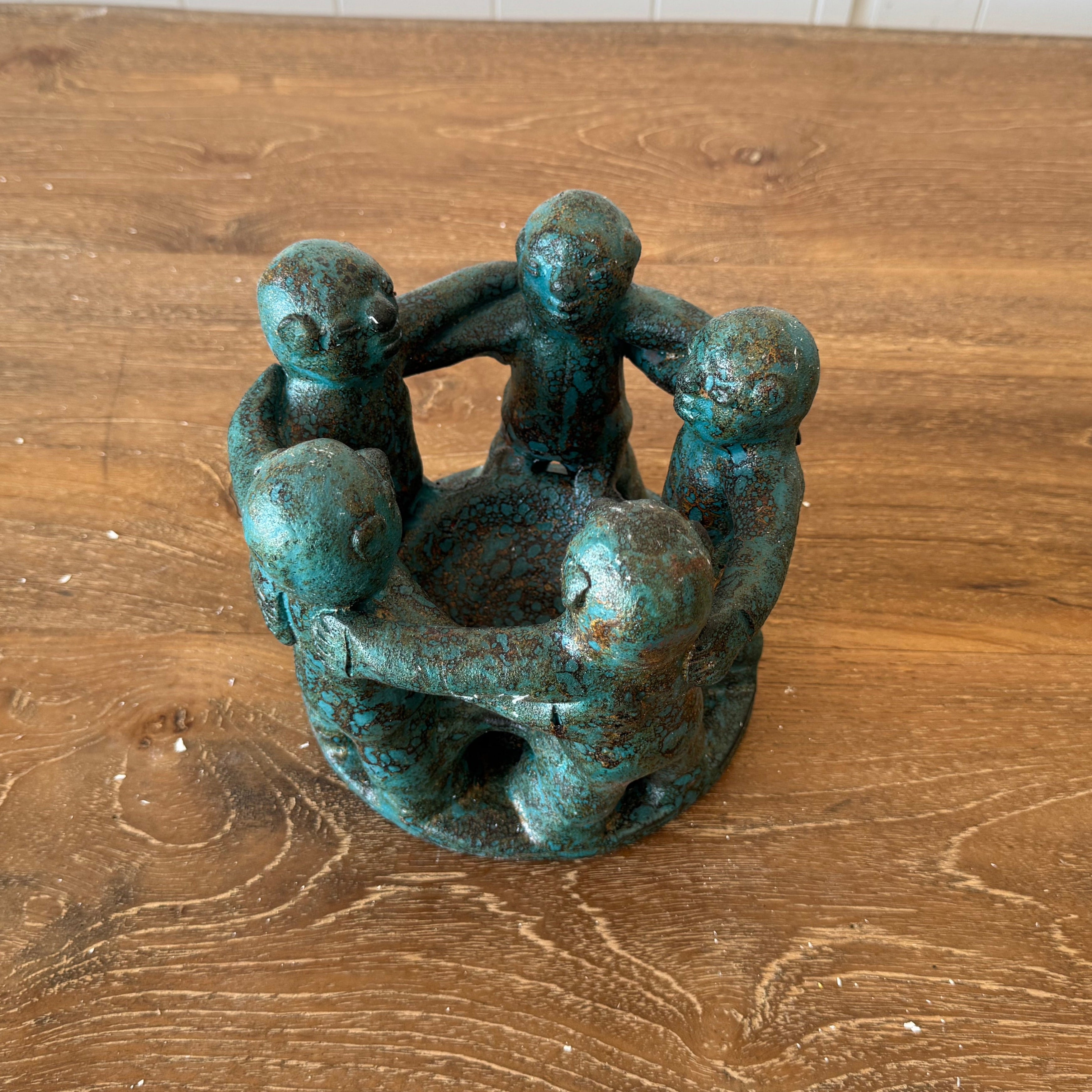 a beautiful green circle of 5 friends candle holder on top of a wooden dining table.