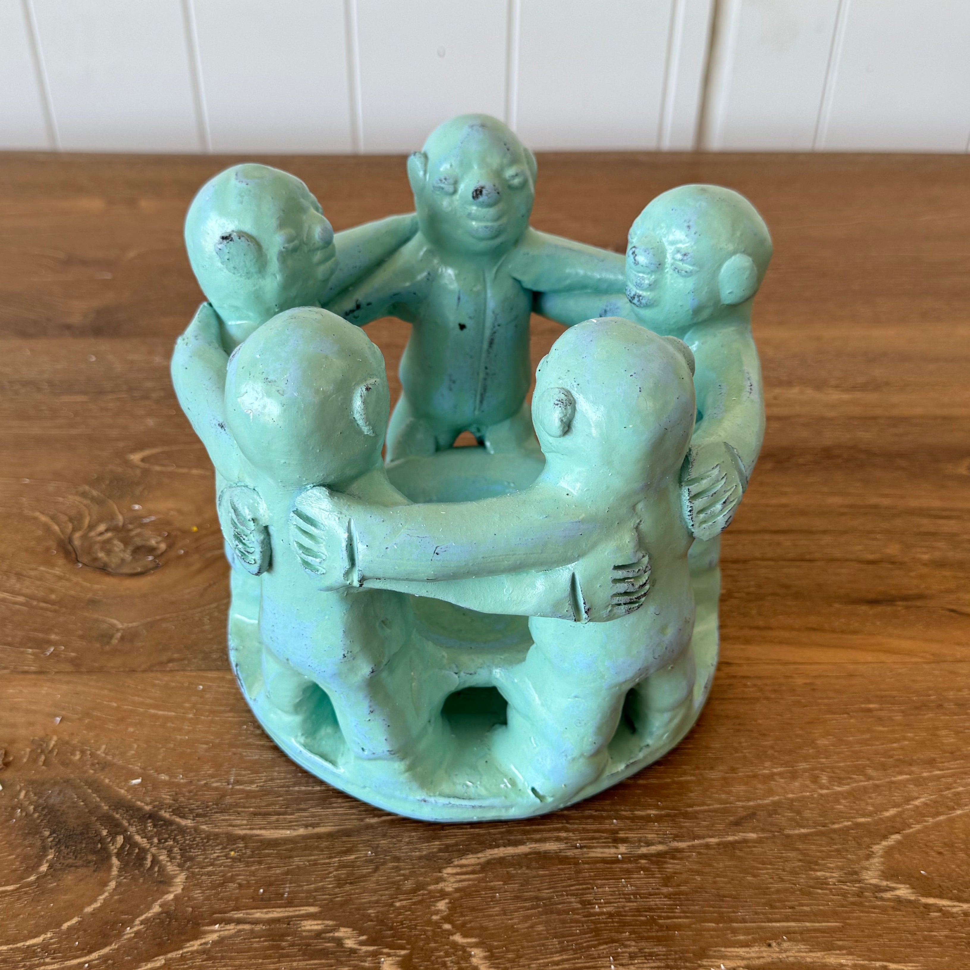 a beautiful Turquoise circle of 5 friends candle holder on top of a wooden dining table.
