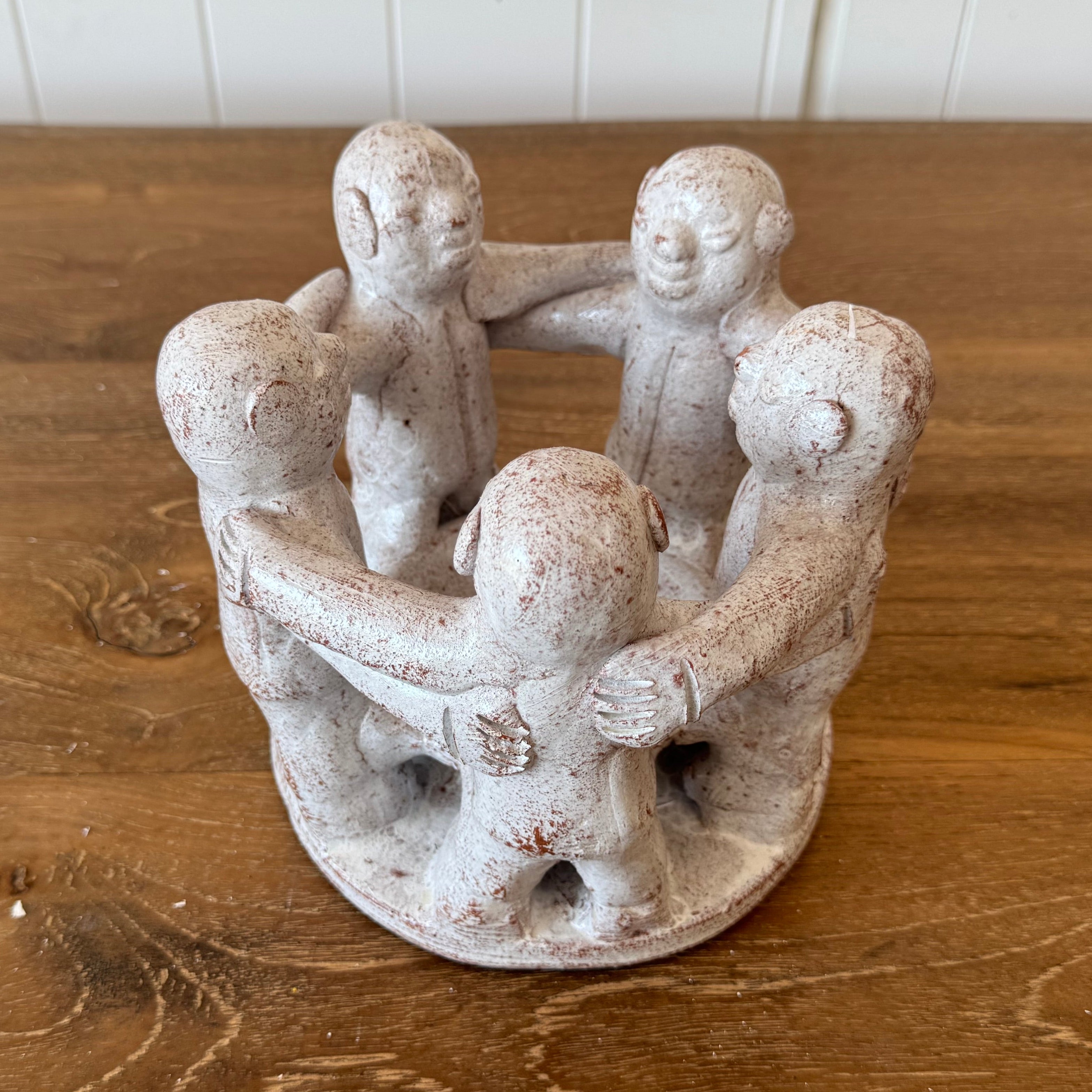 a beautiful white circle of 5 friends candle holder on top of a wooden dining table.