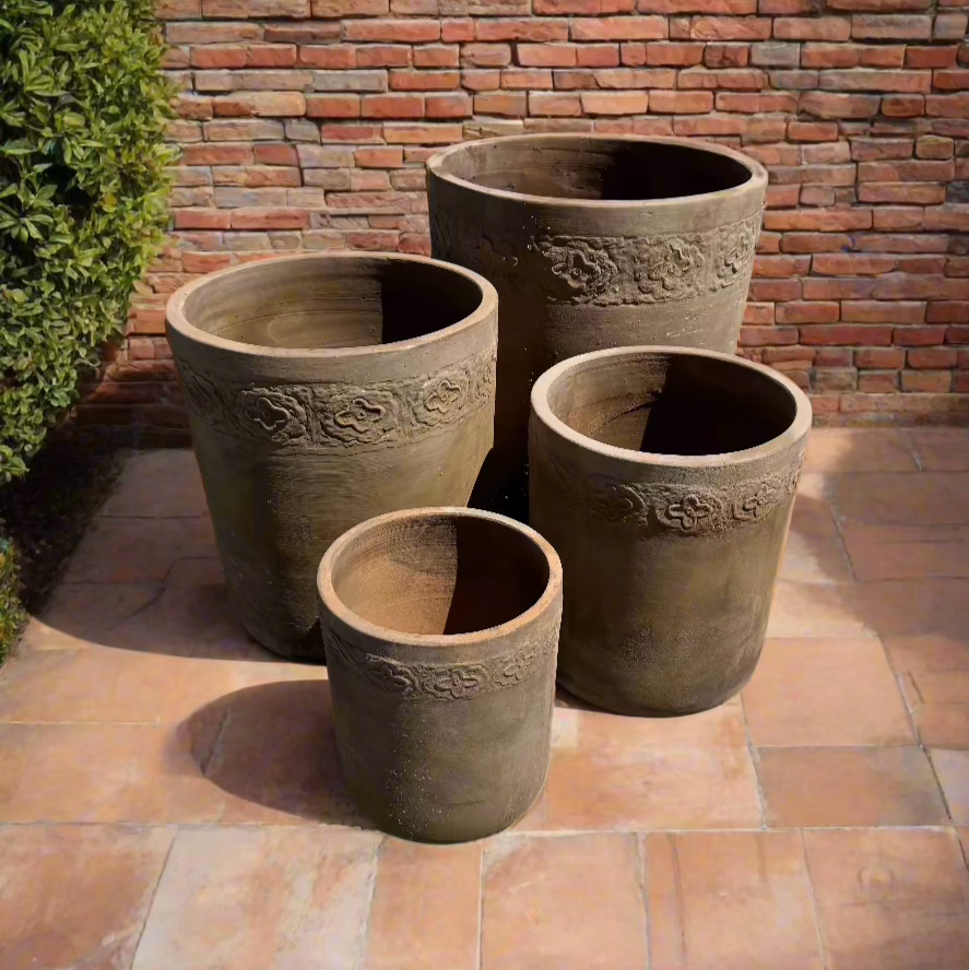 Vietnamese Terracotta tall garden U pots in four different sizes on some terracotta tiles next to a brick wall